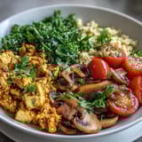 Bright sautéed kale and golden tofu mound over couscous, garnished with cherry tomatoes and fresh parsley.