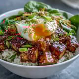 A close-up view of Tofu Jammy Egg Breakfast Bowl with julienned carrots, cucumber slices, and a drizzle of ginger scallion sauce.