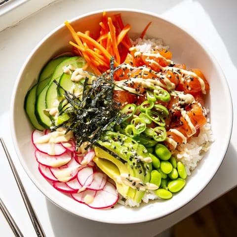 Close-up of a fresh Poke Bowl featuring diced tuna, shredded carrots, and radish, garnished with nori strips and scallions, served with a side of pickled ginger.