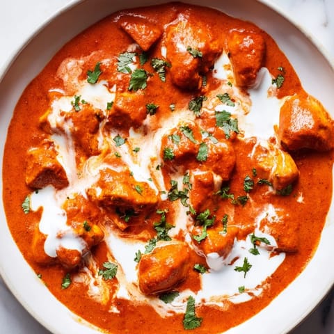 Charred Chicken Tikka Masala simmered in rich tomato cream sauce, garnished with chopped cilantro.
