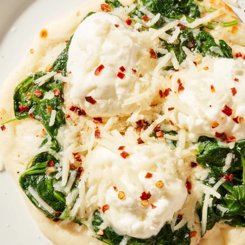 Golden, bubbly cheese covers a thin Spinach Ricotta Pizza with vibrant green spinach and creamy ricotta on a rustic board.