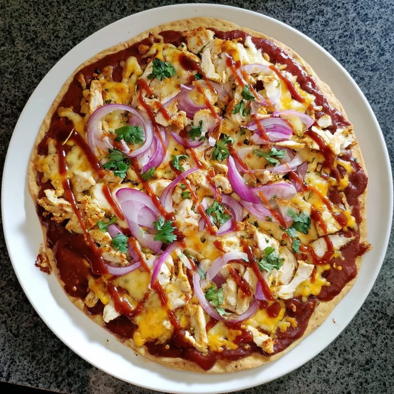 Sizzling grilled chicken and red onions on a cheesy Chicken BBQ Pizza, drizzled with extra barbecue sauce.