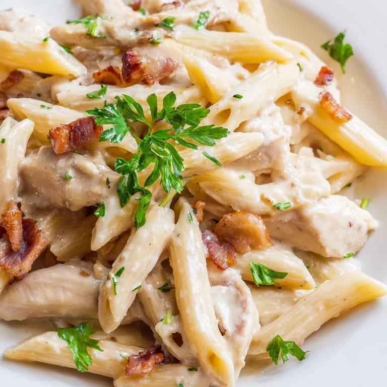 Warm, comforting Creamy Chicken Bacon Penne in a skillet features a rich, glossy sauce, inviting a delicious Italian-American family dinner for four.