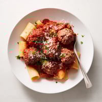 Oven-baked turkey meatballs glistening in a rich tomato sauce, served over twirled spaghetti with fresh basil and grated Parmesan.